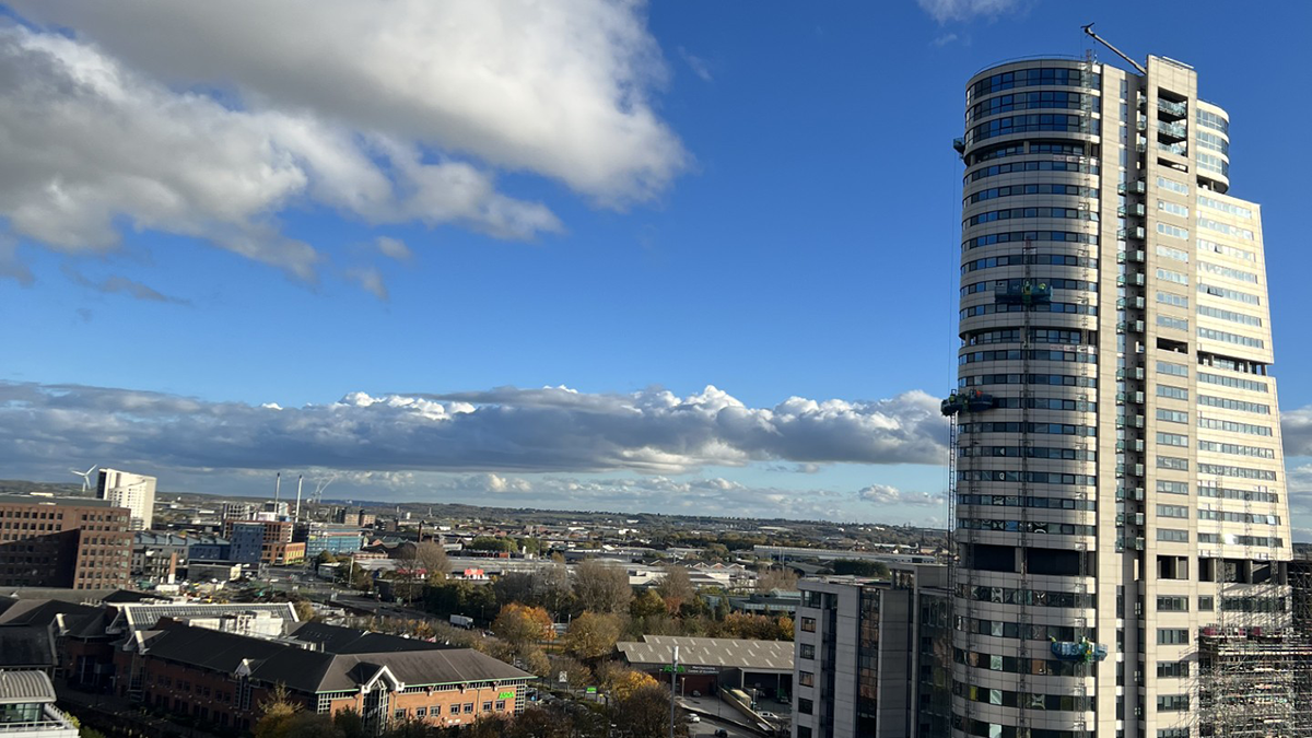 A photo of Leeds from a high point with a large glass building on the right overseeing the city.