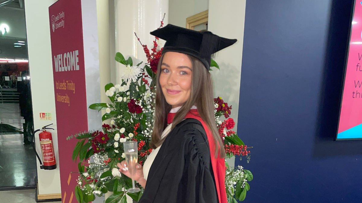 A student in graduation cap and gown smiling.
