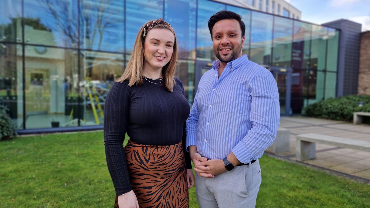 An image of two lecturers in front of the Main Reception at the Main Campus in Horsforth