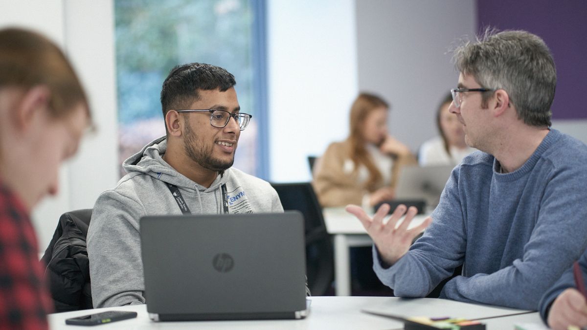 A student sat at a desk listens to an academic