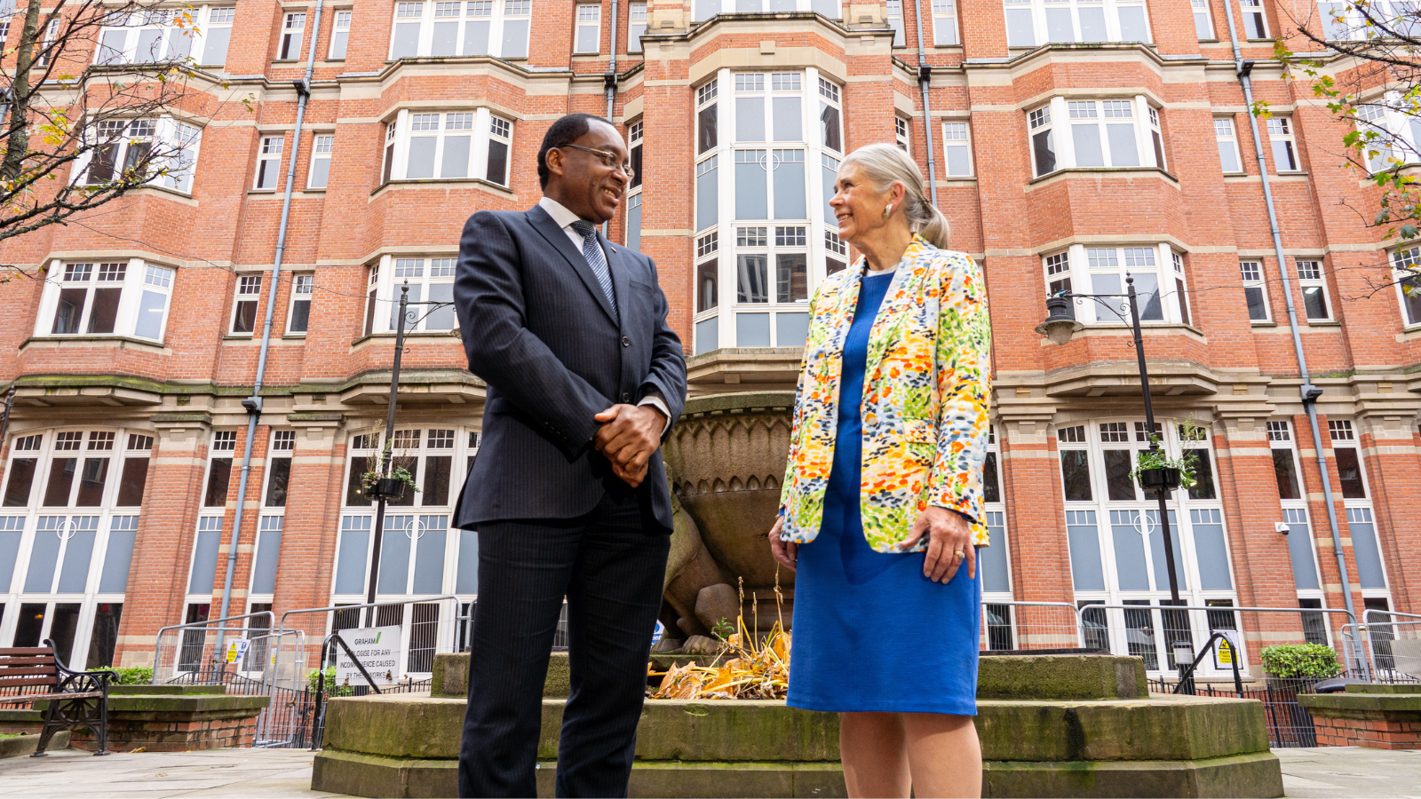 Man and woman, Professor Charles Egbu and Sandi Rhys Jones OBE outside the Leeds Trinity University city centre campus building