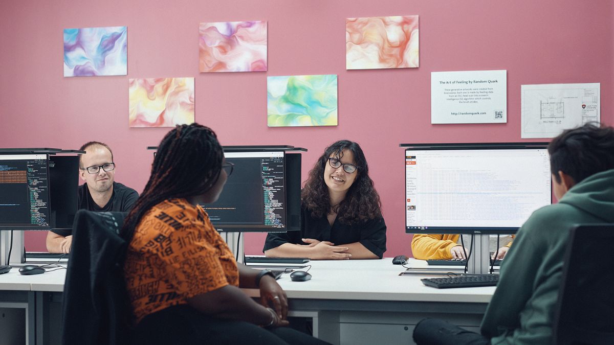 Four students sit in front of computers.