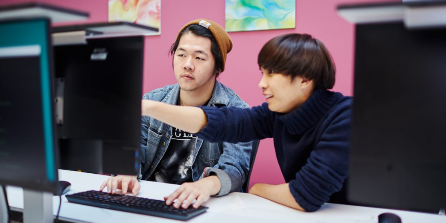 Two male students sat at computer screen.