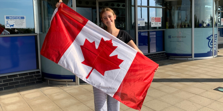 Student holds up Canadian flag at airport departure.