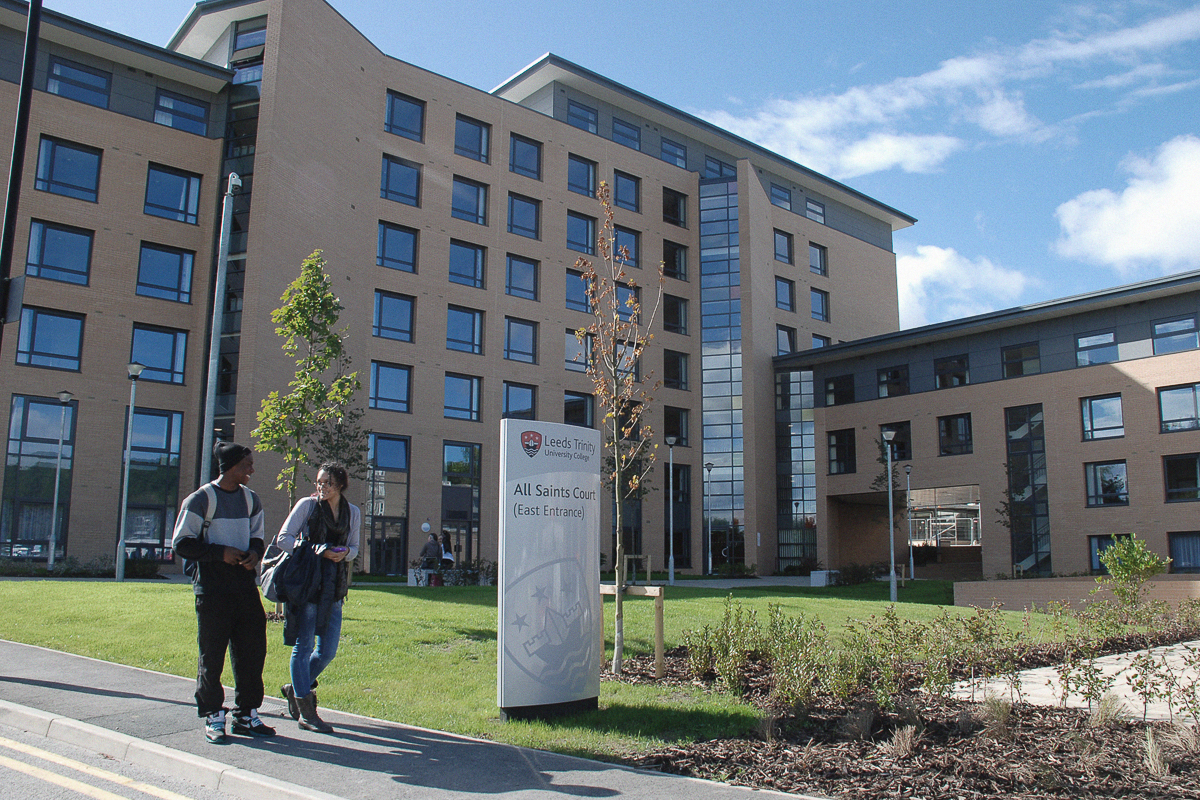 Exterior photograph of All Saints Court with two students walking in front of the building